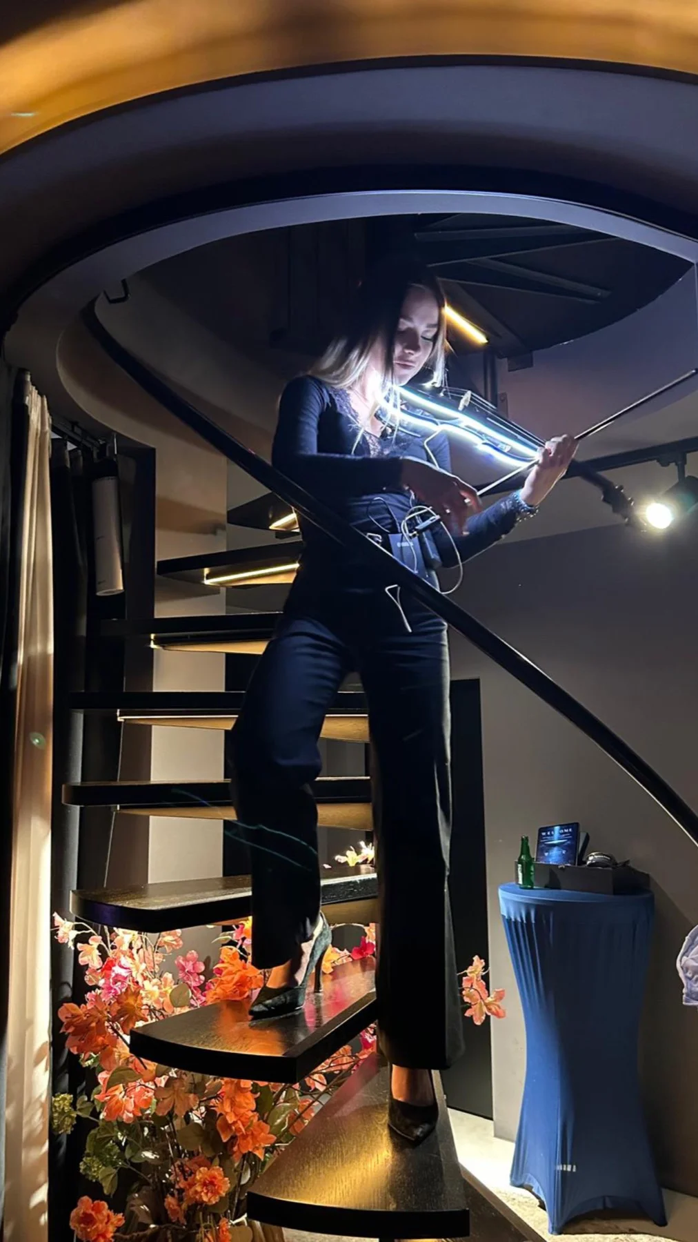 Violinistin spielt auf einer Wendeltreppe eine beleuchtete E-Geige