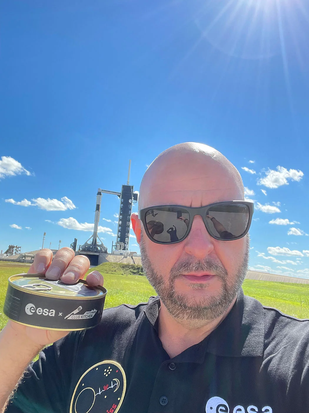 Selfie vor einer Rakete auf der Startrampe, in der Hand eine Dose mit dem Aufdruck „esa × Club Kitchen“