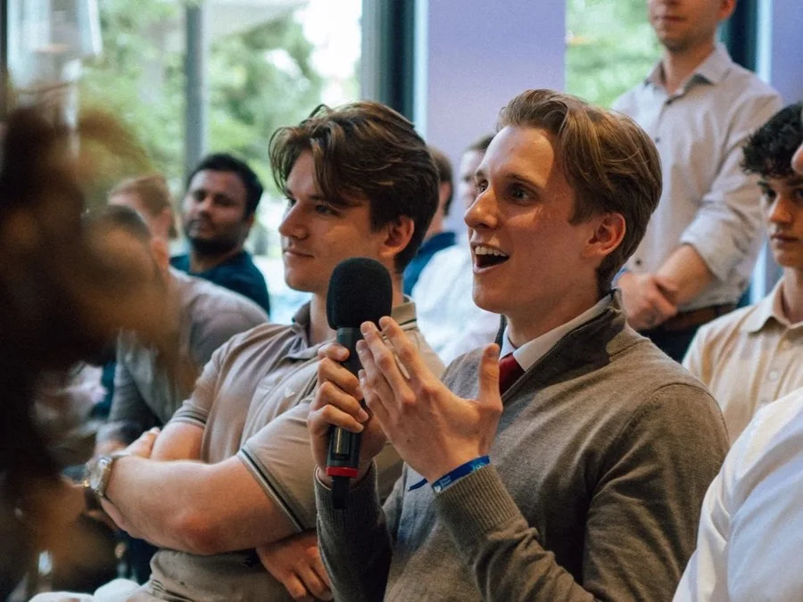Studierende diskutieren, einer spricht in ein Mikrofon