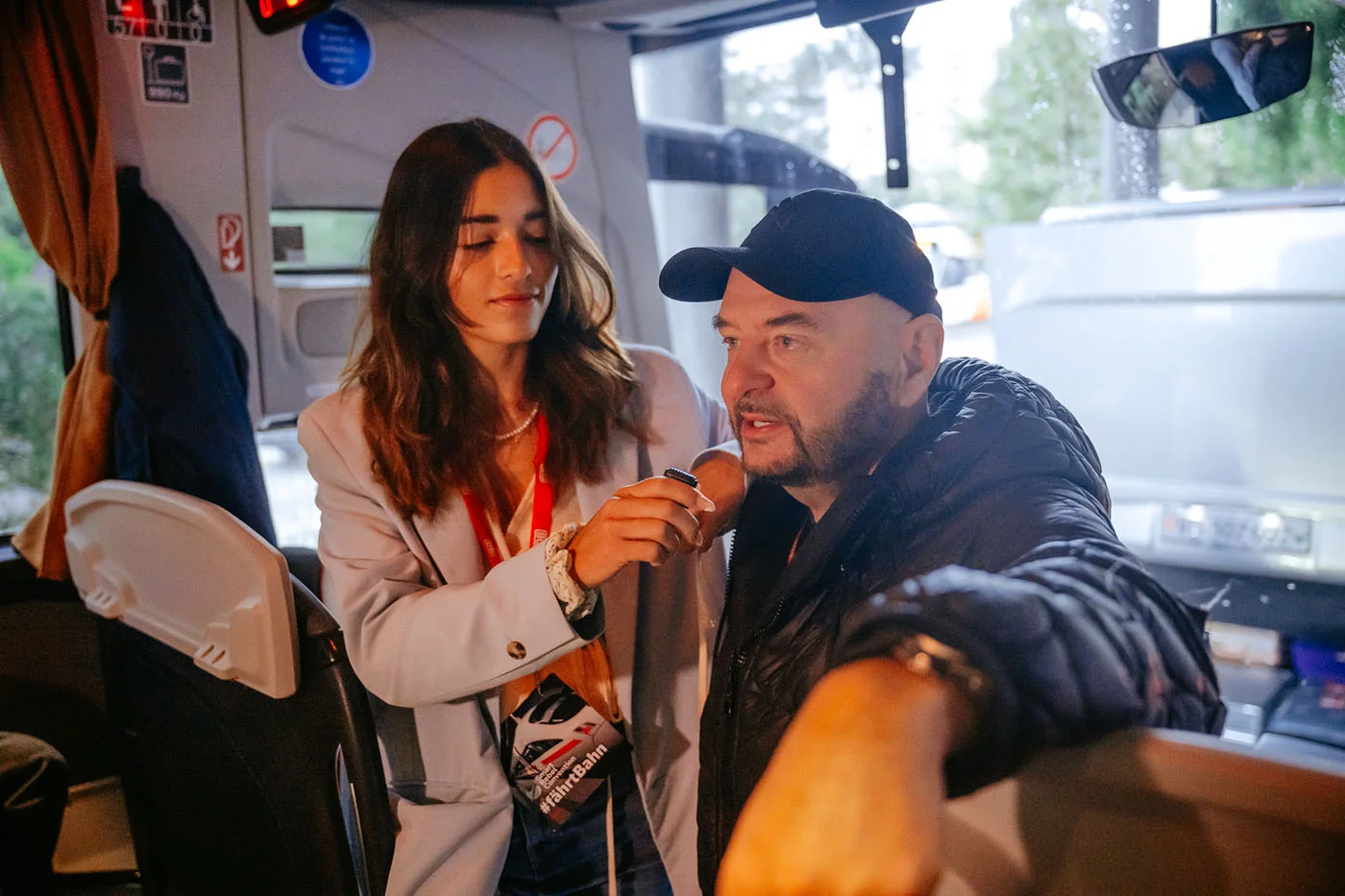 Interviewsituation im Buseinstieg: eine Person hält einer sprechenden Person ein Mikrofon hin