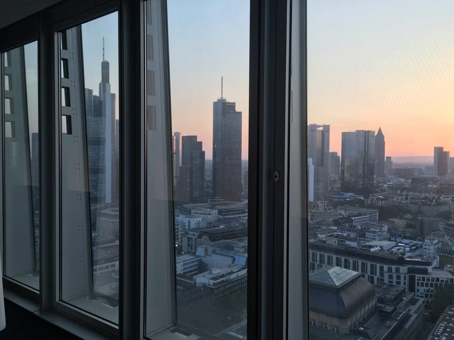 Blick aus einem Hochhausfenster auf die Frankfurter Skyline in der Abenddämmerung
